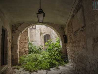 Ad accoglierci un ingresso abbellito da un lampadario in ferro battuto che, attraverso un arco a tutto sesto...